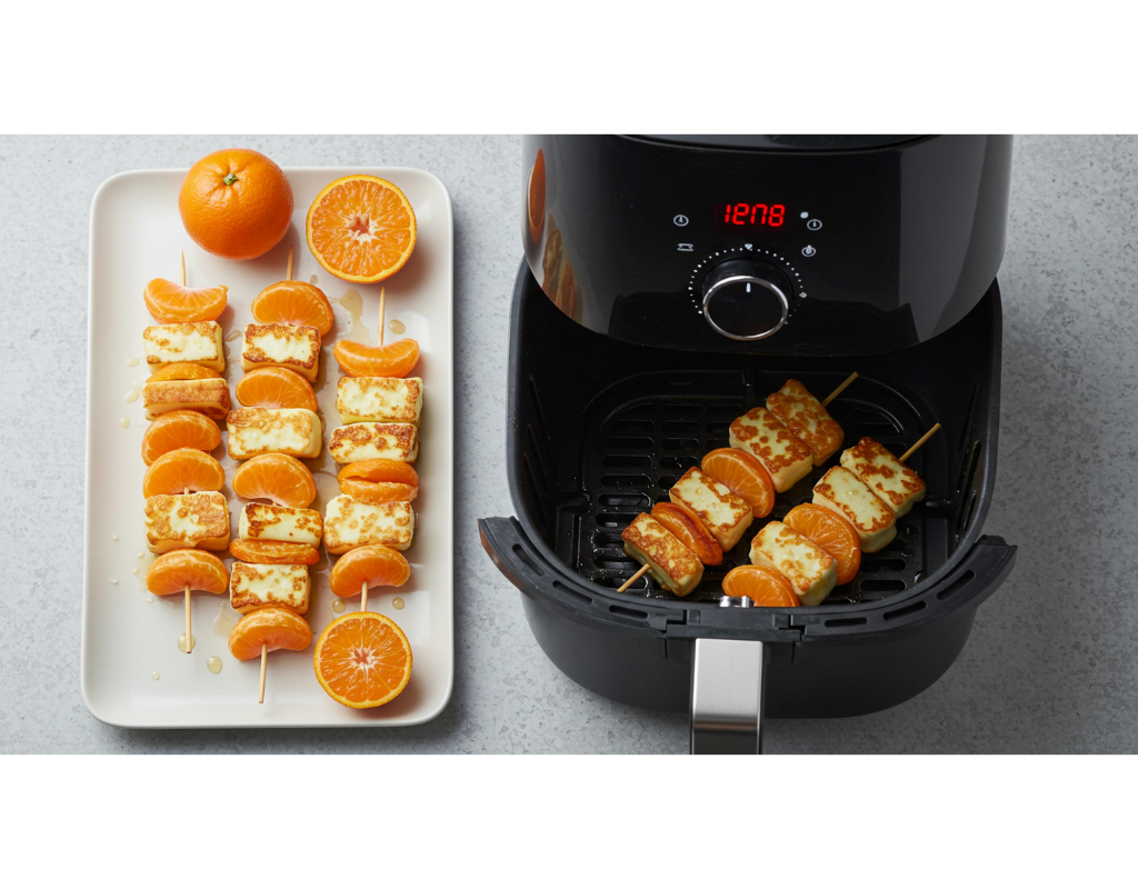 An image of skewers of halloumi and clementine cooking in an air fryer, with the air fryer basket visible and a timer displayed, capturing the cooking process in action.